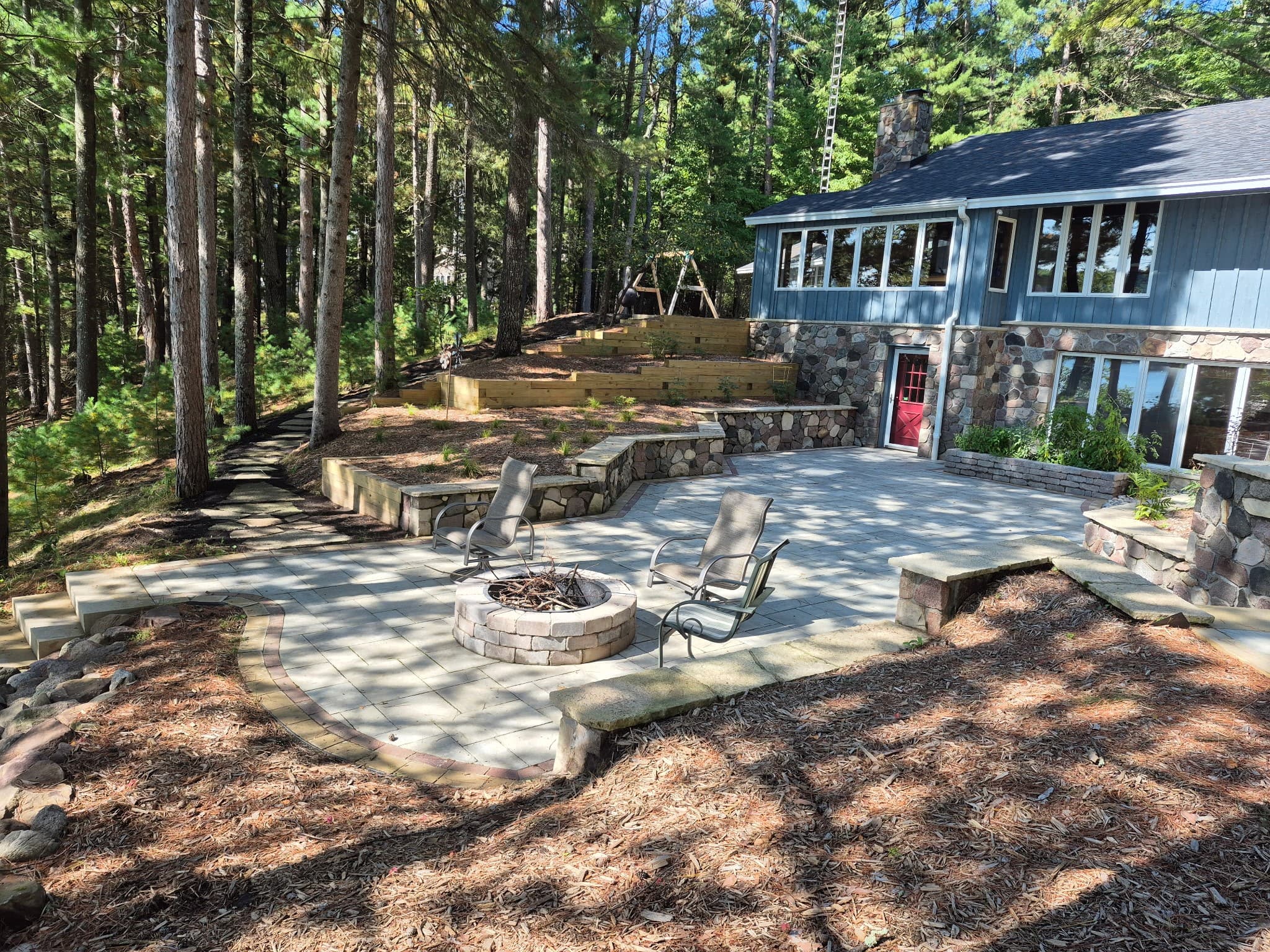 Expansive lakeside paver patio with fire pit and fieldstone seat walls in Wautoma, WI