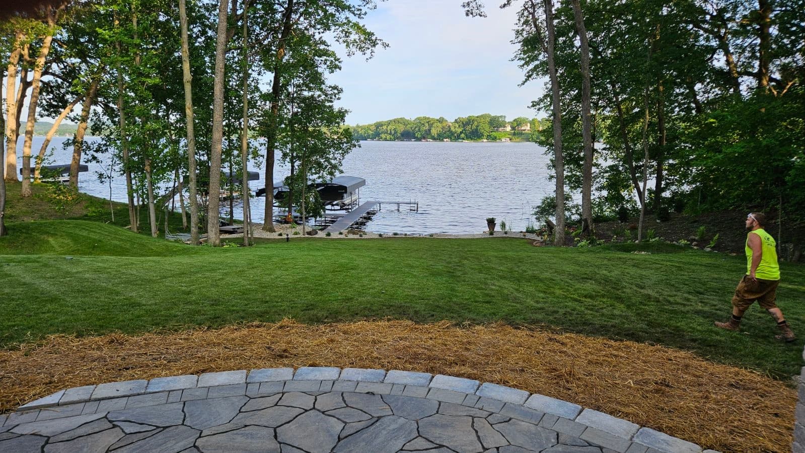 Professional sod lawn installation rolling down to lakefront with green grass and mature trees on Lake Delton