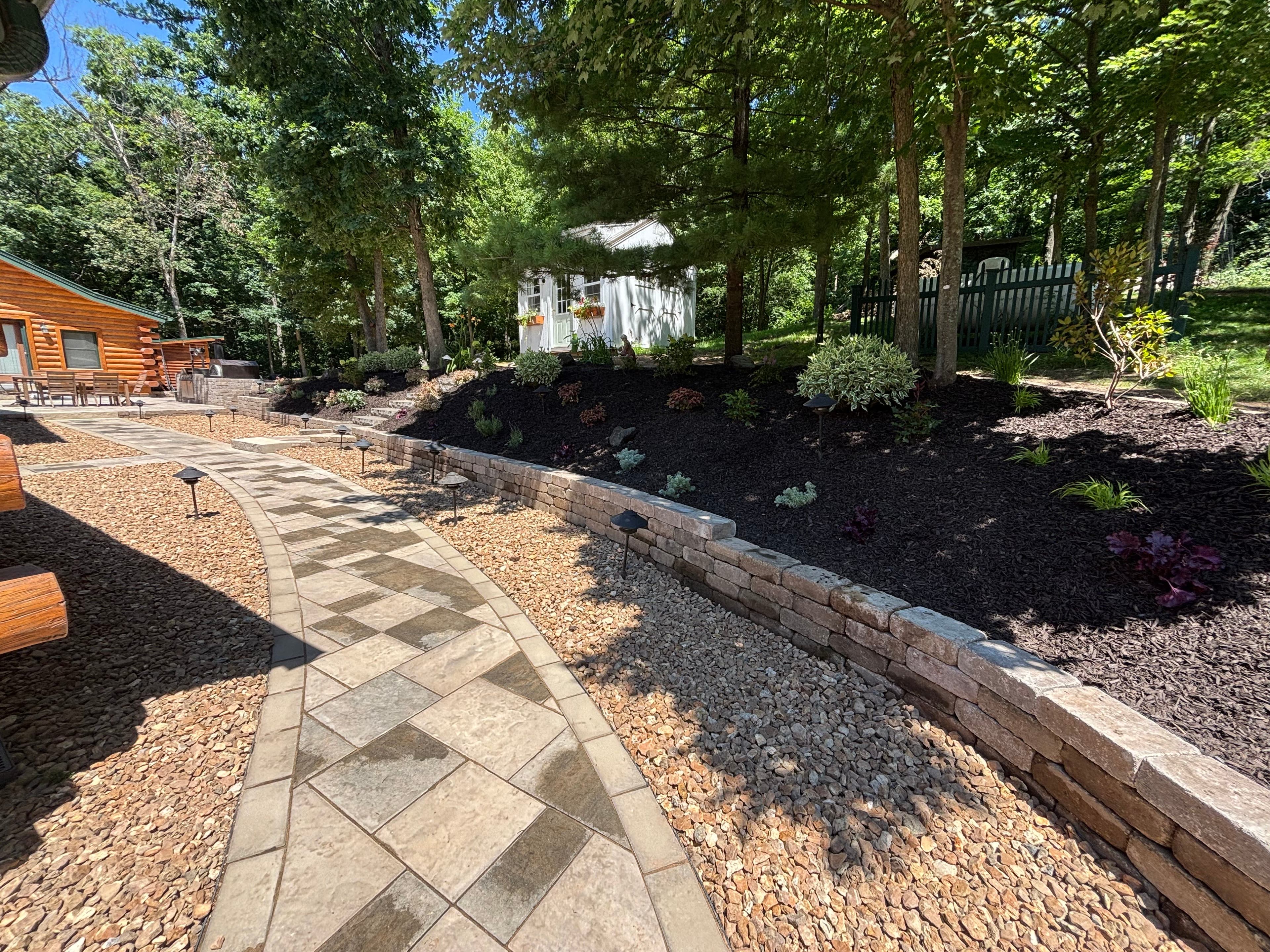 Curved stone walkway with multi-level retaining walls and landscaping in Wisconsin Dells WI backyard featuring professional hardscaping design