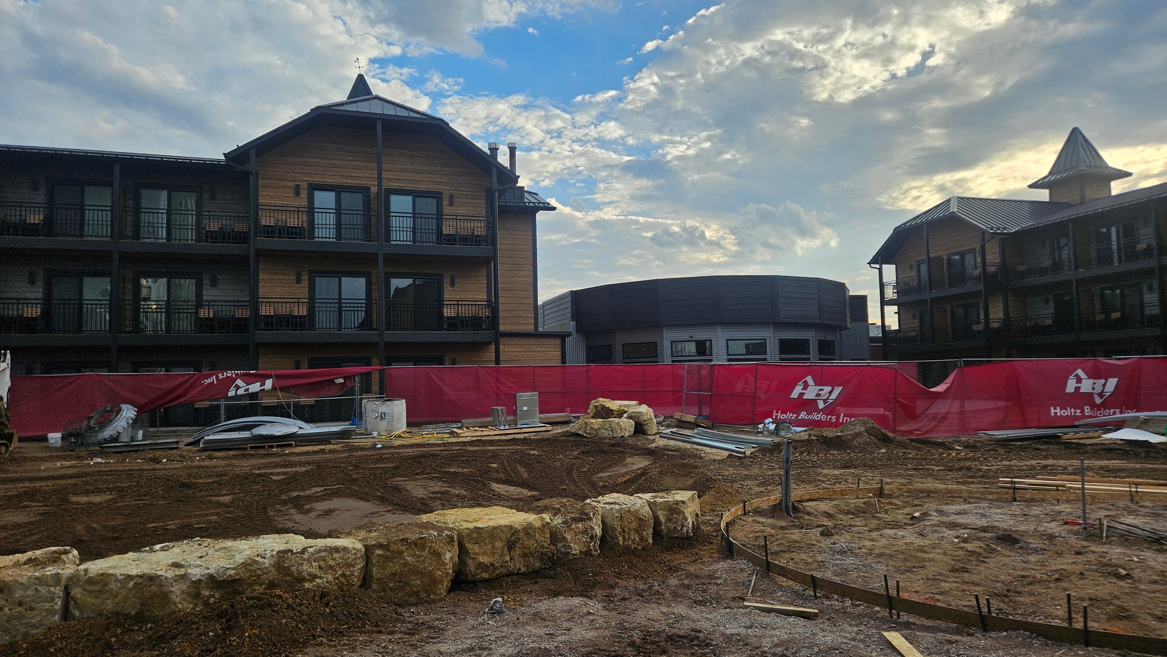 Construction phase showing large limestone boulder retaining walls being installed at The Wisconsin Hotel in Wisconsin Dells with hotel buildings in background