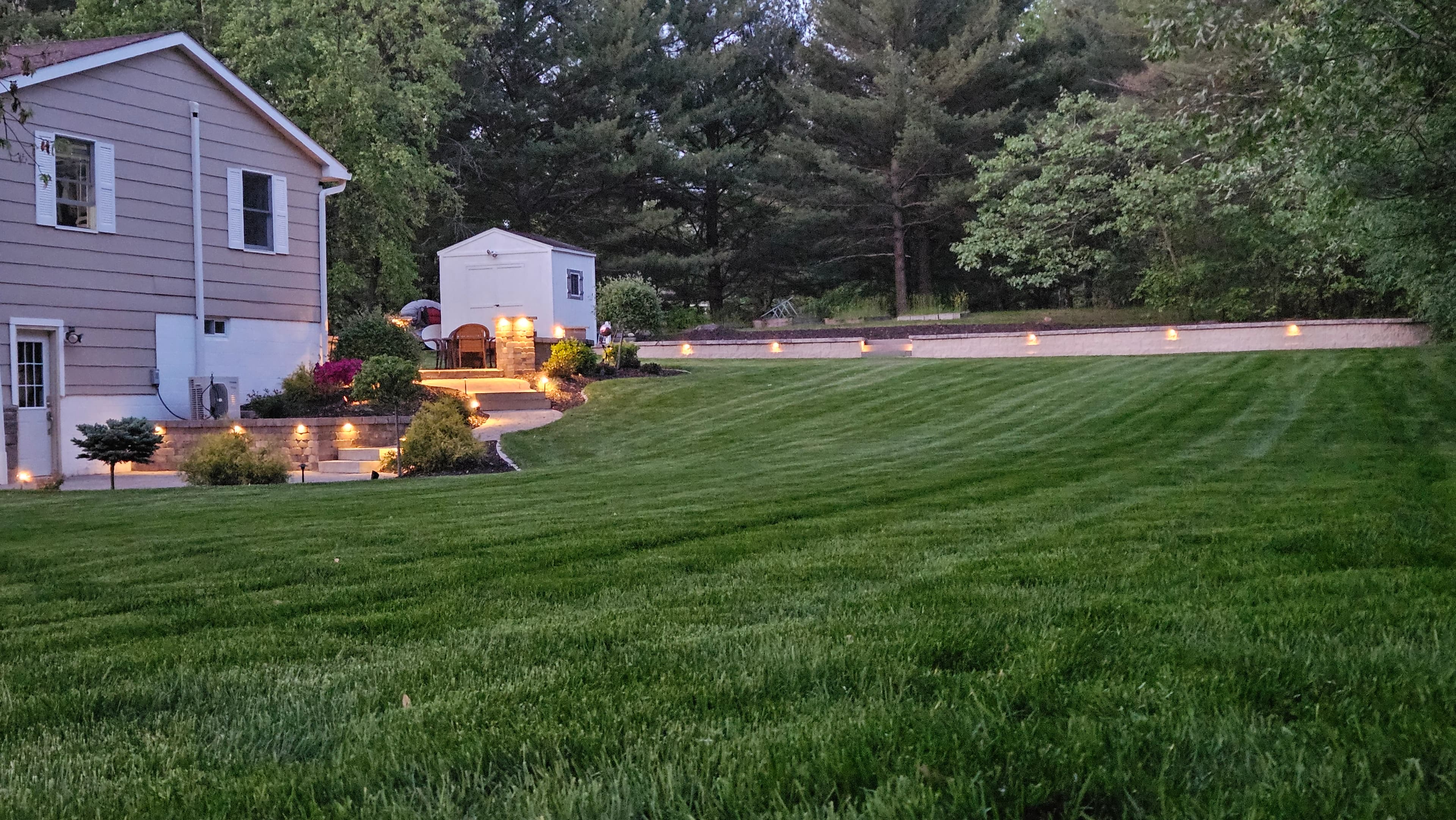 Lush green striped sod lawn with low-voltage landscape lighting at dusk in South-Central Wisconsin